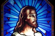 Stained glass window insert showing Christ set against a striking blue background